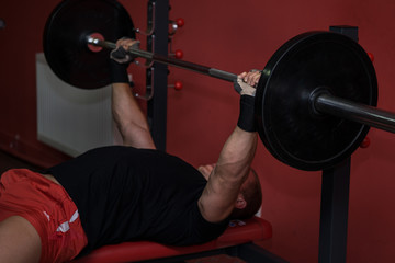 Young muscular man lift weights in the gym on the smith machine with barbell bar with tension. Sport, lifestyle, training and health care concept.