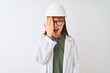 © Krakenimages.com - Young chinese engineer woman wearing coat helmet glasses over isolated white background covering one eye with hand, confident smile on face and surprise emotion.