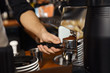 © New Africa - Barista pouring milled coffee from grinding machine into portafilter, closeup
