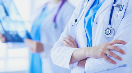 Wall Mural - Close up shoot of doctor's crossed hands and colleague with x-ray on the background.