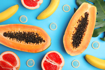 Flat lay composition with condoms and exotic fruits on blue background. Erotic concept