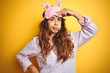 © Krakenimages.com - Young woman wearing pajama and sleep mask standing over yellow isolated background worried and stressed about a problem with hand on forehead, nervous and anxious for crisis