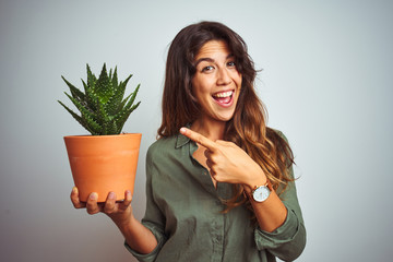 Young beautiful woman holding cactus pot over white isolated background very happy pointing with hand and finger