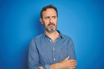 Poster - Handsome middle age senior man with grey hair over isolated blue background looking sleepy and tired, exhausted for fatigue and hangover, lazy eyes in the morning.