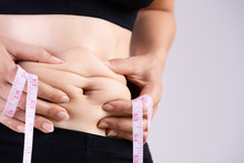 Fat Woman Hand Holding Excessive Belly Fat With Measuring Tape. Healthcare And Woman Diet Lifestyle Concept To Reduce Belly And Shape Up Healthy Stomach Muscle.