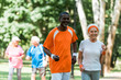 © LIGHTFIELD STUDIOS - selective focus of african american senior man and happy retired woman exercising near pensioners outside