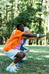 Wall Mural - selective focus of african american man doing sit ups with pensioners in park