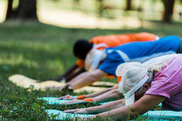 Wall Mural - selective focus of multicultural retired women and men stretching on fitness mats in park