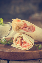 Wall Mural - Fresh tortilla wrap with vegetables and salmon on wooden cutting board