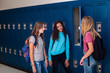 © Brocreative - Candid photo of Three Junior High school Students talking together in a school hallway. Diverse Female school girls smiling and having fun together during a break at school