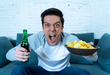 Wall Mural - Excited and happy young man sitting on the couch watching TV. TV programming concept