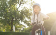 Smiling boy in safety helmet riding his bike.asian child on a bicycle at asphalt road in summer. Bike in the park