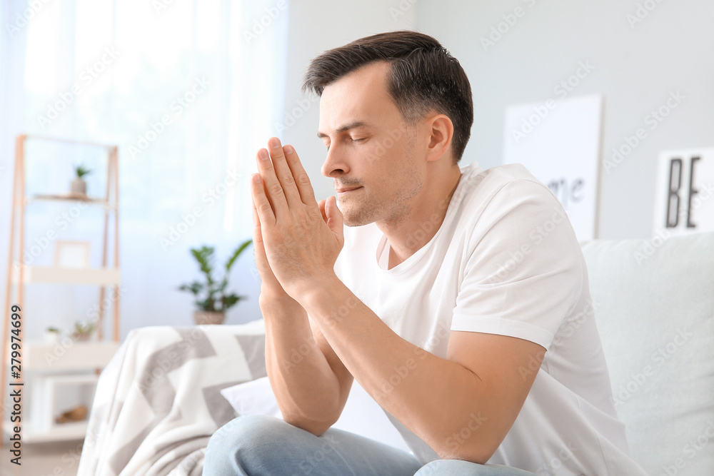 Religious man praying to God at home