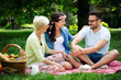 © NDABCREATIVITY - Young woman and man with grandmother smilling in a park on a sunny day