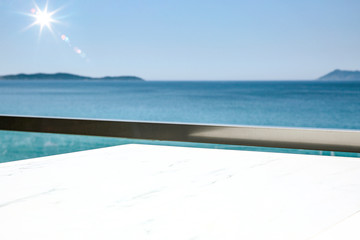 Poster - A white table background on a balcony  on a beautiful sunny blue sky and ocean view,