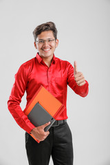 Wall Mural - Handsome Indian/Asian Male college student with book, Wearing red shirt and standing against white background,
