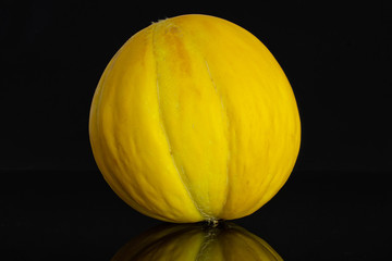 One whole fresh yellow melon canary isolated on black glass