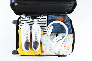 Wall Mural - Open suitcase fully packed with folded women's clothing and accessories on the floor. Woman packing for tropical vacation concept. Female luggage w/ things. Background, close up, copy space, top view.