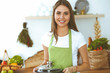 © rogerphoto - Young happy woman cooking soup in the kitchen. Healthy meal, lifestyle and culinary concept. Smiling student girl preparing vegetarian meal at home