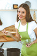 © rogerphoto - Young happy woman cooking soup in the kitchen. Healthy meal, lifestyle and culinary concept. Smiling student girl preparing vegetarian meal at home
