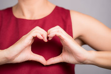 Closeup Hands Of A Beautiful Woman In Stylish Red Outfit Making Heart Shape Gesture On Her Chest. Positive Human Emotion Expression, Love, Caring, Body Language, Health, Charity, Donation Concept.