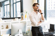 © Drobot Dean - Image of joyful businesslike man talking on cellphone while working in office