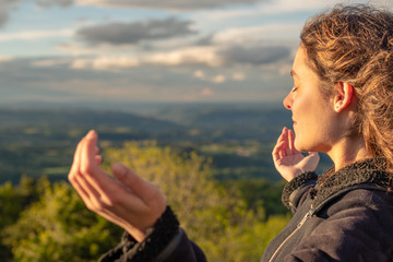 Wall Mural - Christian worship and praise. A young woman is praying and worshiping in the evening.