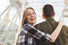 Rear View Of Smiling Woman Standing With Her Boyfriend In Front Of Ferris Wheel