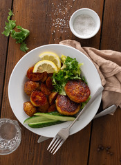 Wall Mural - Dinner plate with vegetarian food. Fresh vegetarian cutlets with new potatoes and salad on wooden table top view