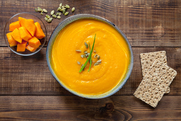 Wall Mural - Pumpkin soup with cream on wood texture, top view. Vegan food.