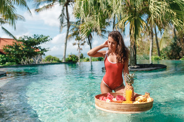 Wall Mural - Pretty smiling young woman have breakfast in the swimming pool