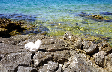 Sea coast with interesting stones and rocks on the front and turquoise and blue sea water in the background