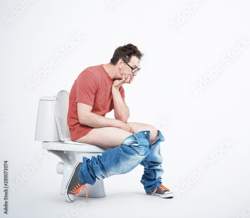 Fotomural Man in casual clothes and glasses is sitting on the toilet