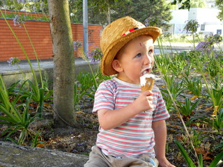 Wall Mural - little boy in straw hat eats ice cream