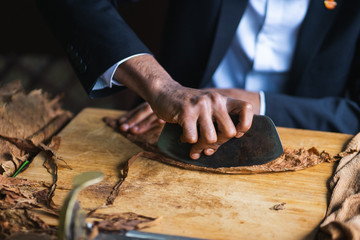 Process of making traditional cigars from tobacco leaves with hands using a mechanical device and press. 