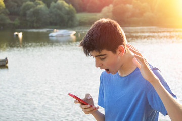 Canvas Print - young boy with expression of surprise with the mobile phone outdoors