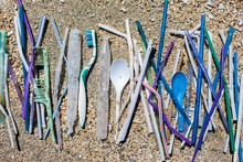 Heap Of Different Plastic Waste: Straws And Single-use Spoons, Toothbrush And Comb Collected On The Beach On Sand Background. Environmental Pollution Problem, A Lot Of Disposable Waste, Say No Plastic