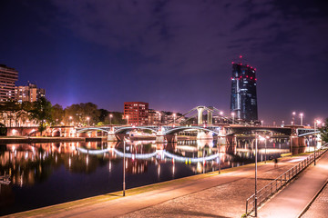 Fototapete - City of Frankfurt am Main in Germany seen at night with lights, river, buildings and bridge.