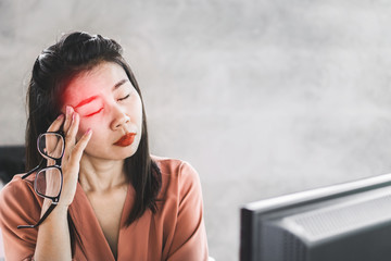 Wall Mural - Asian woman worker suffering from eye pain working on computer screen, hand holding eyeglasses 