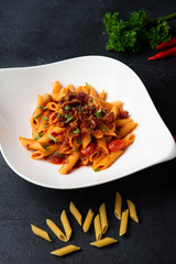 Sticker - Penne pasta in tomato sauce with bacon on dark background