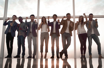 Canvas Print - group of young professionals standing in an office with a large window