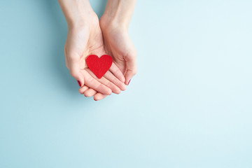 a person holding red heart in hands, donate and family insurance concept, on aquamarine background, 