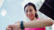 © tirachard - Healthy beautiful young Asian Athlete woman setting and checking progress looking heart rate monitor on smart watch while running in urban city. Lifestyle women exercise in the city concept.