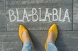 Female feet with text bla-bla-bla written on grey sidewalk