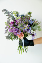 A Bouquet Of Flowers In A Hand On A White Wall
