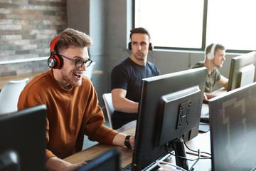 Wall Mural - Men playing video games in internet cafe