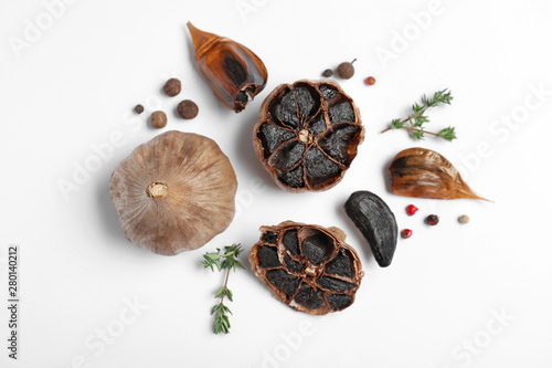 Fotografía Aged black garlic with thyme and peppercorns on white background, view from abov