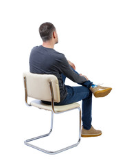 Side view of a man sitting on a chair.