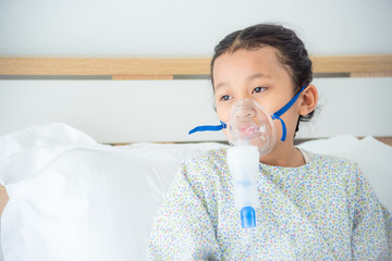 young asian sick girl sitting on bed with oxygen mask