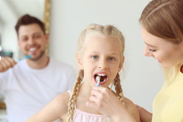 Wall Mural - Mother teaching little girl to clean teeth at home